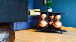 A modern living room with a dark sofa, a coffee table with spherical objects, a potted plant, and a framed picture on the wall. - Eco Camp Norway - Hostel (Smøla)