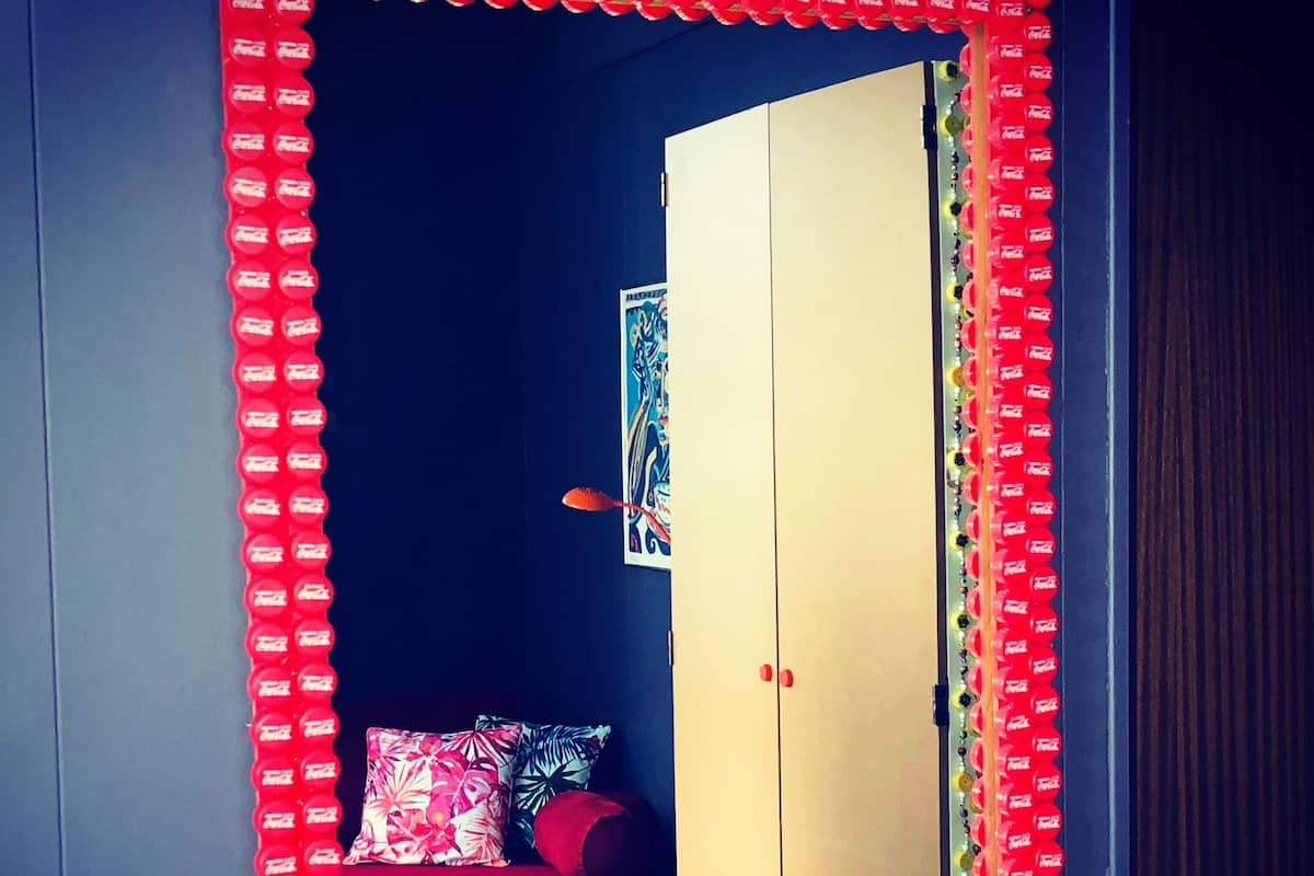 A room with a wardrobe, a bed, and a mirror with a red frame.