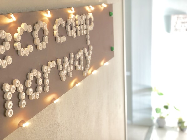 A bulletin board with a message spelled out using white buttons, illuminated by string lights. - Eco Camp Norway - Hostel (Smøla)