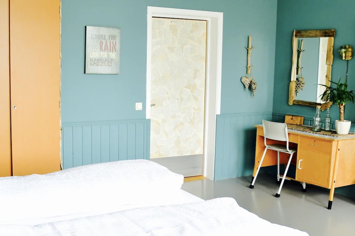 A bedroom with a bed, a desk, and a dresser.