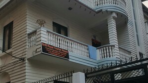 A two-story building with a balcony on the upper floor. There is a sign in front that reads "BnB Royal Tourist House" with contact information.
