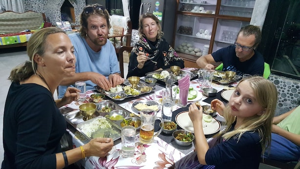 A group of people dining at a table with various dishes, glasses, and utensils.