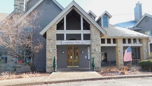 A building with a stone facade, a prominent entrance with a sign reading "Long Hollow Point Inn," and an American flag displayed outside.