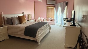A bedroom with a bed, bedside tables, a dresser, a television, and a window with curtains.
