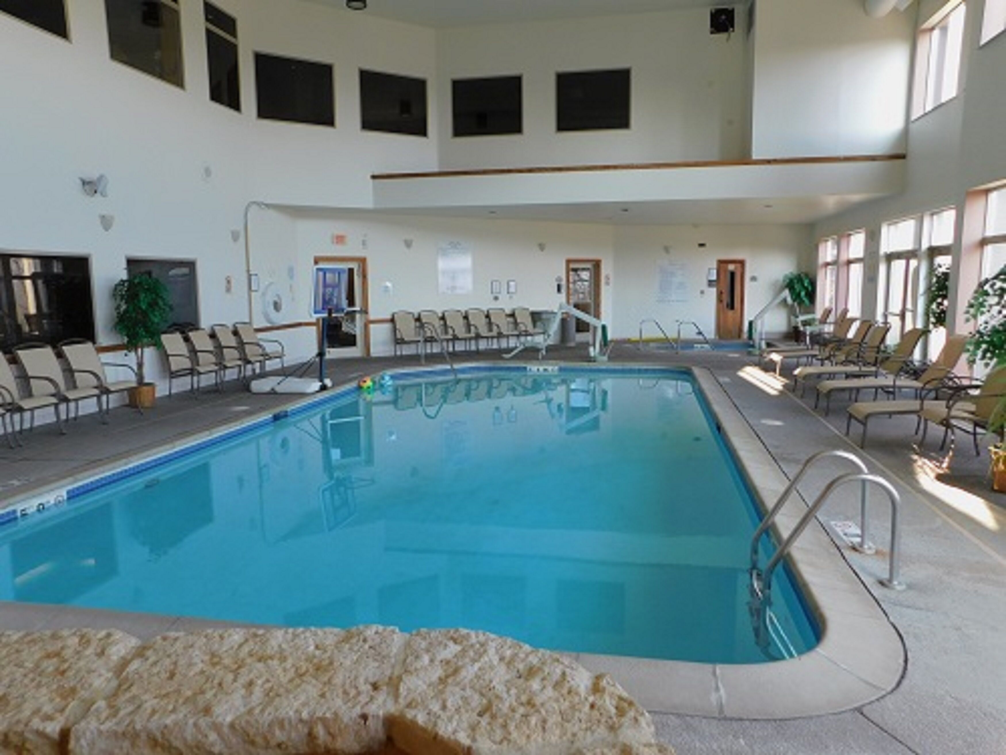 An indoor swimming pool with a clear view of the pool area, including the poolside chairs and the pool's edge.