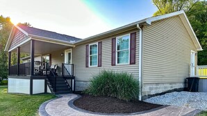 A single-story house with a covered porch, a front yard with a stone pathway, and a small garden bed.