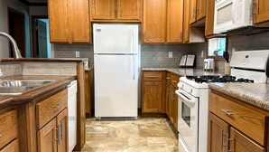 A modern kitchen with wooden cabinets, a white refrigerator, a stove, and a microwave.