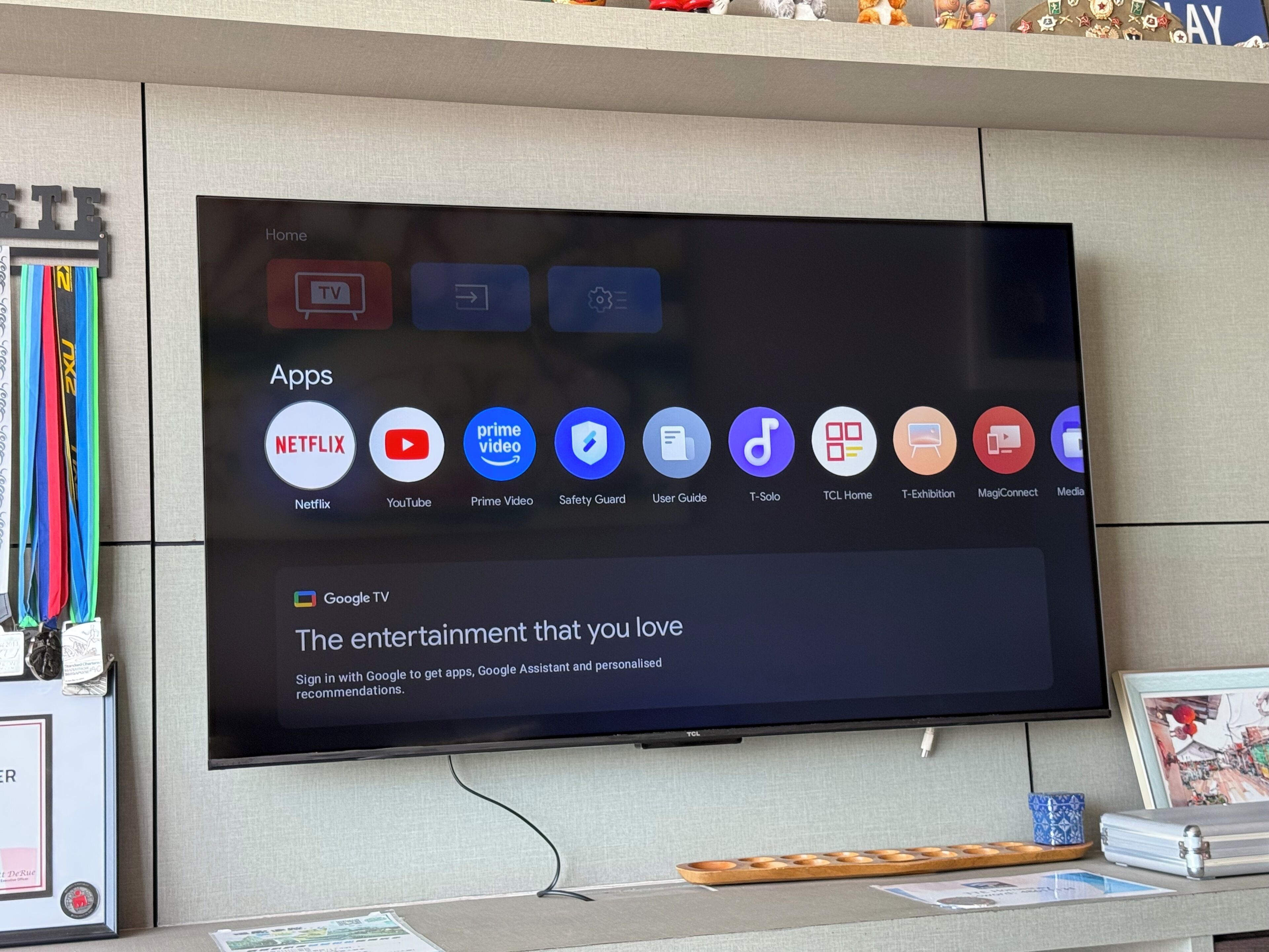 Ein flachbildfernseher an der Wand, der einen Homescreen mit verschiedenen App-Symbolen zeigt, darunter Netflix, YouTube und Prime Video.