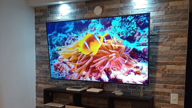 A flat-screen TV mounted on a stone-patterned wall with a wooden shelf below. - SUPERHOST APARTAMENTO, EXCELENTE UBICACION TULIPAN (Cúcuta)