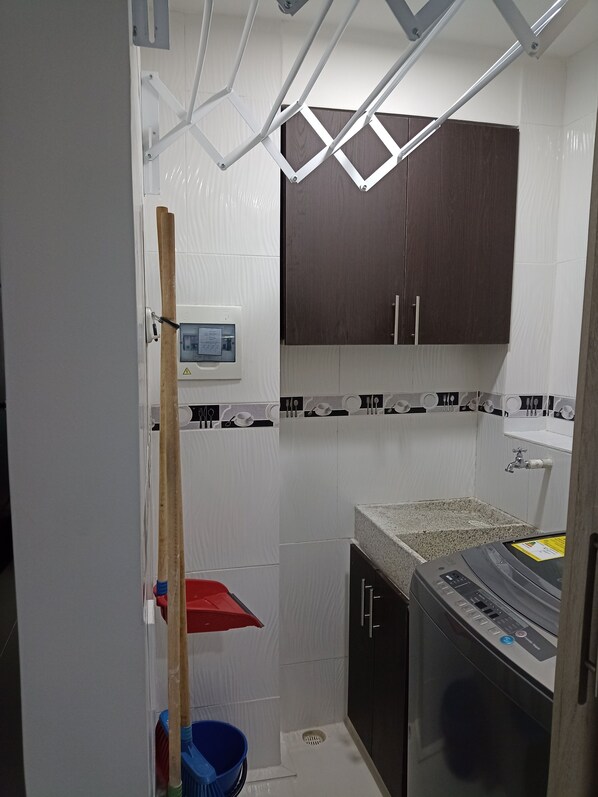 A compact kitchen with white and black patterned tiles, a built-in oven, and a wooden cabinet.