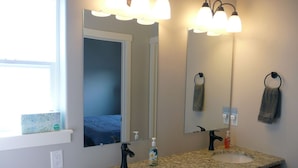 Een badkamer met een dubbele wastafel, twee hanglampen, een spiegel en een handdoekrek.