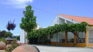 A building with a red-tiled roof, a covered porch with a metal railing, and a clear blue sky. - Tapada da Beirã - Rural house (2-3 persons) (Marvão)