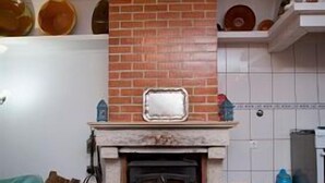 A living room with a fireplace, tiled floor, and a brick wall. - Tapada da Beirã - Rural house (2-3 persons) (Marvão)