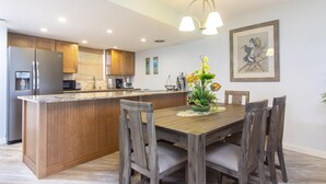 A modern kitchen with wooden cabinets, a central island, and a dining area with a wooden table and chairs.