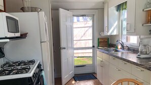 A compact kitchen with a stove, microwave, and refrigerator. - Three bedroom cottage-Only .2 miles to Sea Street Beach (Dennis Port)