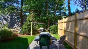 A backyard with a wooden fence, a picnic table, and two chairs. - Three bedroom cottage-Only .2 miles to Sea Street Beach (Dennis Port)