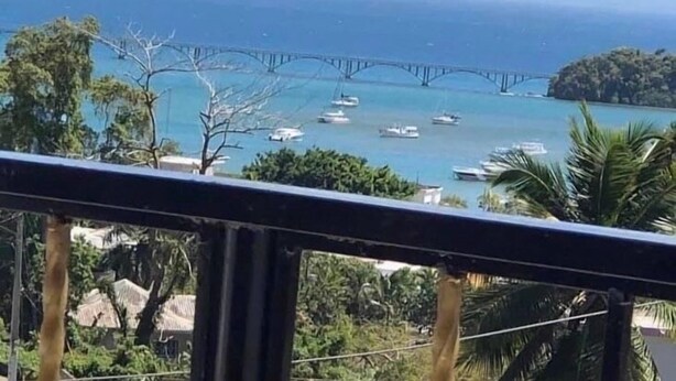 A coastal view with a bridge, boats, and lush greenery. - Jazmin Apartments Vacations (Samaná)