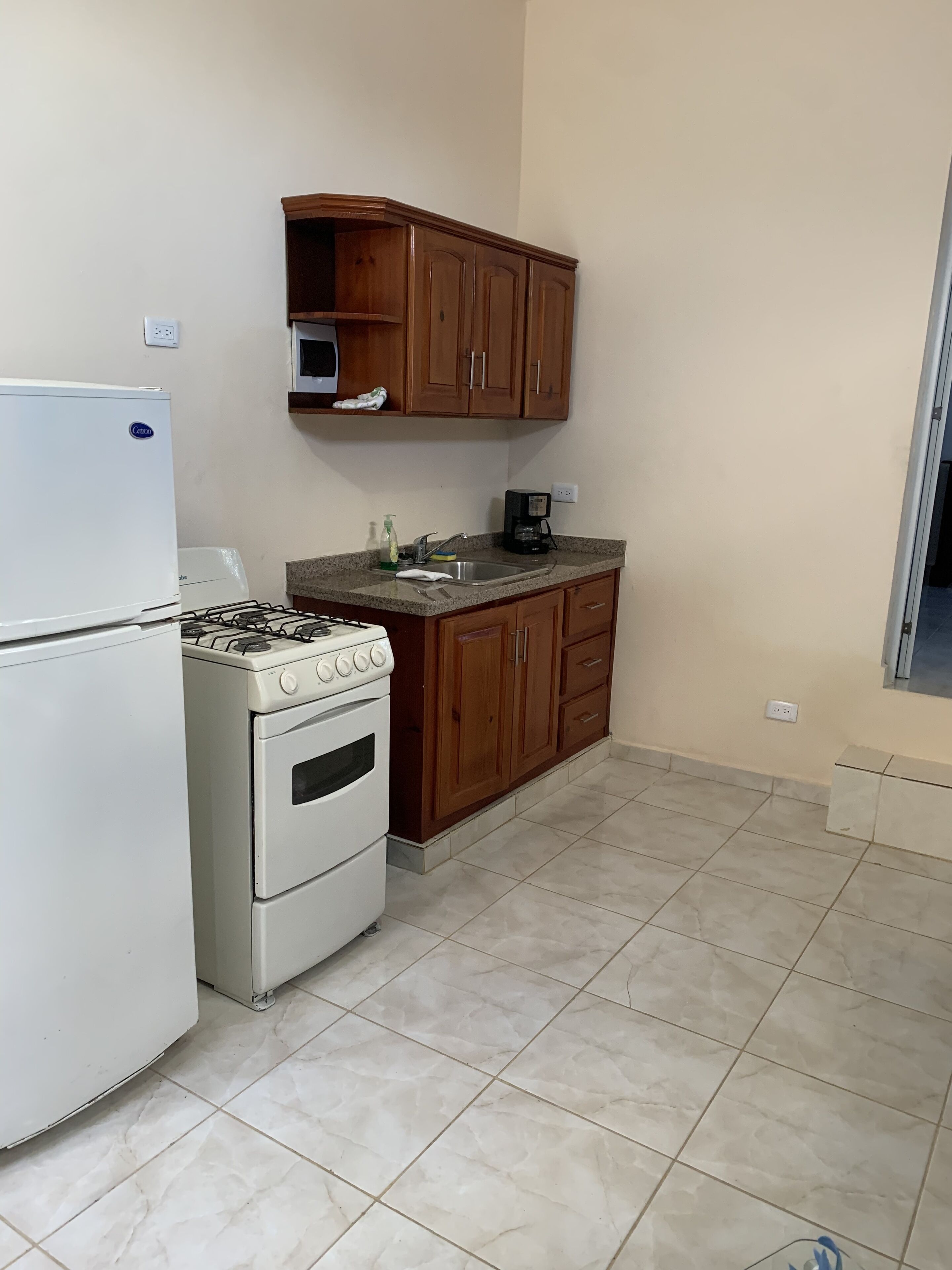 A kitchen with a white refrigerator, a stove, and wooden cabinets.