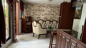 A spacious living room with a stone wall, a sofa, a dining table, and wooden cabinets. - Jazmin Apartments Vacations (Samaná)
