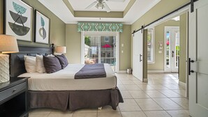 A bedroom with a bed, a ceiling fan, and a view of the outside.
