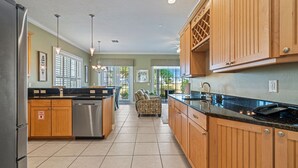 A spacious kitchen with wooden cabinets, a stainless steel refrigerator, and a large island with a sink.