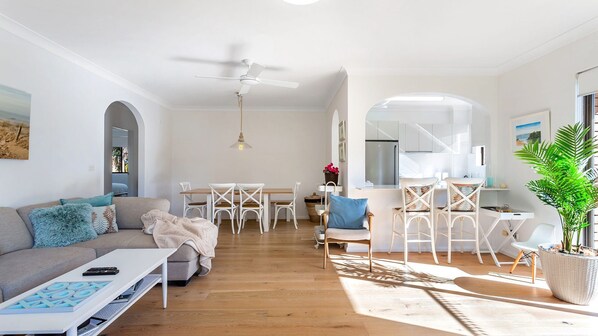 A modern living room with a sofa, coffee table, and dining area with chairs. - Three bedroom unit at Little Beach (Nelson Bay)