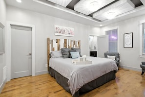 A bedroom with a bed, a wooden headboard, a bedside table, a chair, a mirror, and a wall with a framed quote. - Bachelorette HQ + Roof Deck, Walk to Broadway 5bath, 3kings,4 Queen, 8 twins (Nashville)