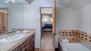 A bathroom with a double sink, a bathtub, and a mirror. - Penthouse At The Peaks 826 (Mountain Village)