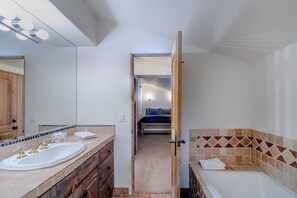 A bathroom with a double sink, a bathtub, and a mirror.