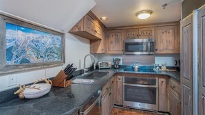 A kitchen with wooden cabinets, a stainless steel microwave, and a sink. - Penthouse At The Peaks 826 (Mountain Village)