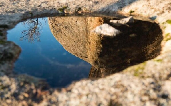 A natural rock formation with a reflective water surface.