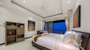 A modern bedroom with a large bed, a ceiling fan, an air conditioning unit, a wardrobe, and a view of the outside. - Ban Nai Fan: 3 Bed Pool Villa w/ Magnificent Sea View (Ko Samui)