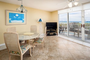 Relax in this inviting living room with a round table, wicker chairs, and a large flat-screen TV.