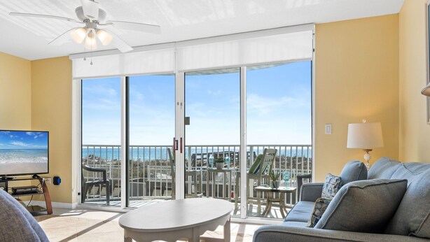 A balcony with a view of the ocean, a ceiling fan, a TV, and a sofa with a lamp. - IP 208: Sunglasses Required - Your Beachfront Sanctuary Starts Here! (Fort Walton Beach)