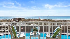 A pool area with lounge chairs, a small table with a plant and glasses, and a view of the beach and ocean. - IP 208: Sunglasses Required - Your Beachfront Sanctuary Starts Here! (Fort Walton Beach)