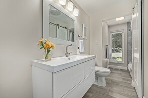 Ein modernes Badezimmer mit einem weißen Waschtisch, einem großen Spiegel und einer Toilette.