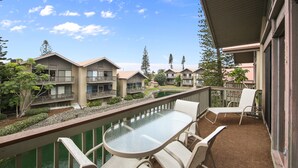 A balcony with a glass table and chairs, overlooking a courtyard with a pool and multiple buildings. - Steps to#1 rated Beach in USA Spacious2+2Condo,pool,garageTranquil Setting (Siesta Key)