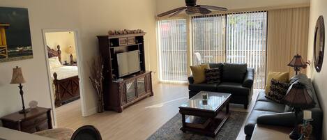 A spacious living room with a dark wooden entertainment center, a black leather sofa, and a glass coffee table.