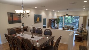 A spacious dining area with a large wooden table and chairs, a chandelier, and artwork on the walls. - Steps to#1 rated Beach in USA Spacious2+2Condo,pool,garageTranquil Setting (Siesta Key)