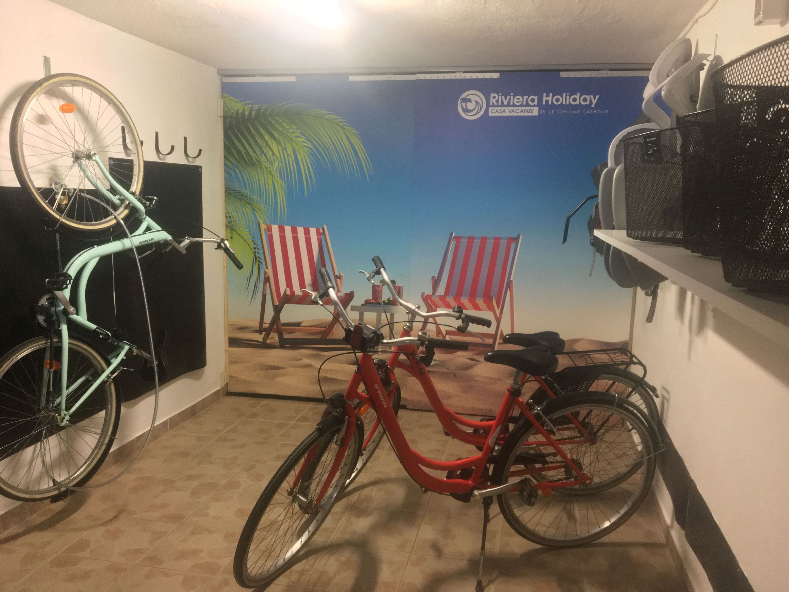 A room with two bicycles, a beach-themed mural, and a sign for Riviera Holiday.