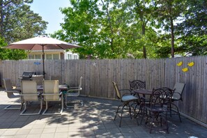 Une terrasse extérieure avec une table et des chaises, un barbecue et une clôture en bois agrémentée de décorations.