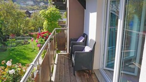 A balcony with wicker chairs, a wooden deck, and a glass door. - Apartment Holz by Interhome (Pians)