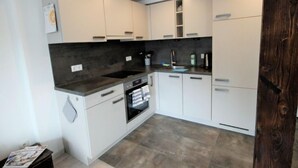 A modern kitchen with white cabinets, a dark countertop, and a built-in oven. - Apartment Holz by Interhome (Pians)