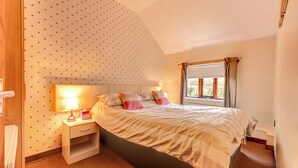 Un dormitorio con cama, mesita de noche, lámpara y ventana con cortinas.