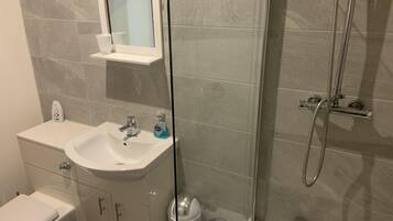 Un baño con lavamanos, espejo y retrete blancos.