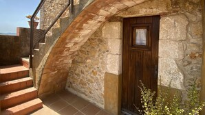 A stone building with a wooden door and a metal staircase. - Holiday rental townhouse in Begur, Centre (Begur)
