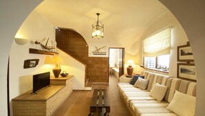 A cozy living room with a sofa, TV, and a wooden bench. There's a staircase leading to another room, and a window with curtains. - Holiday rental townhouse in Begur, Centre (Begur)