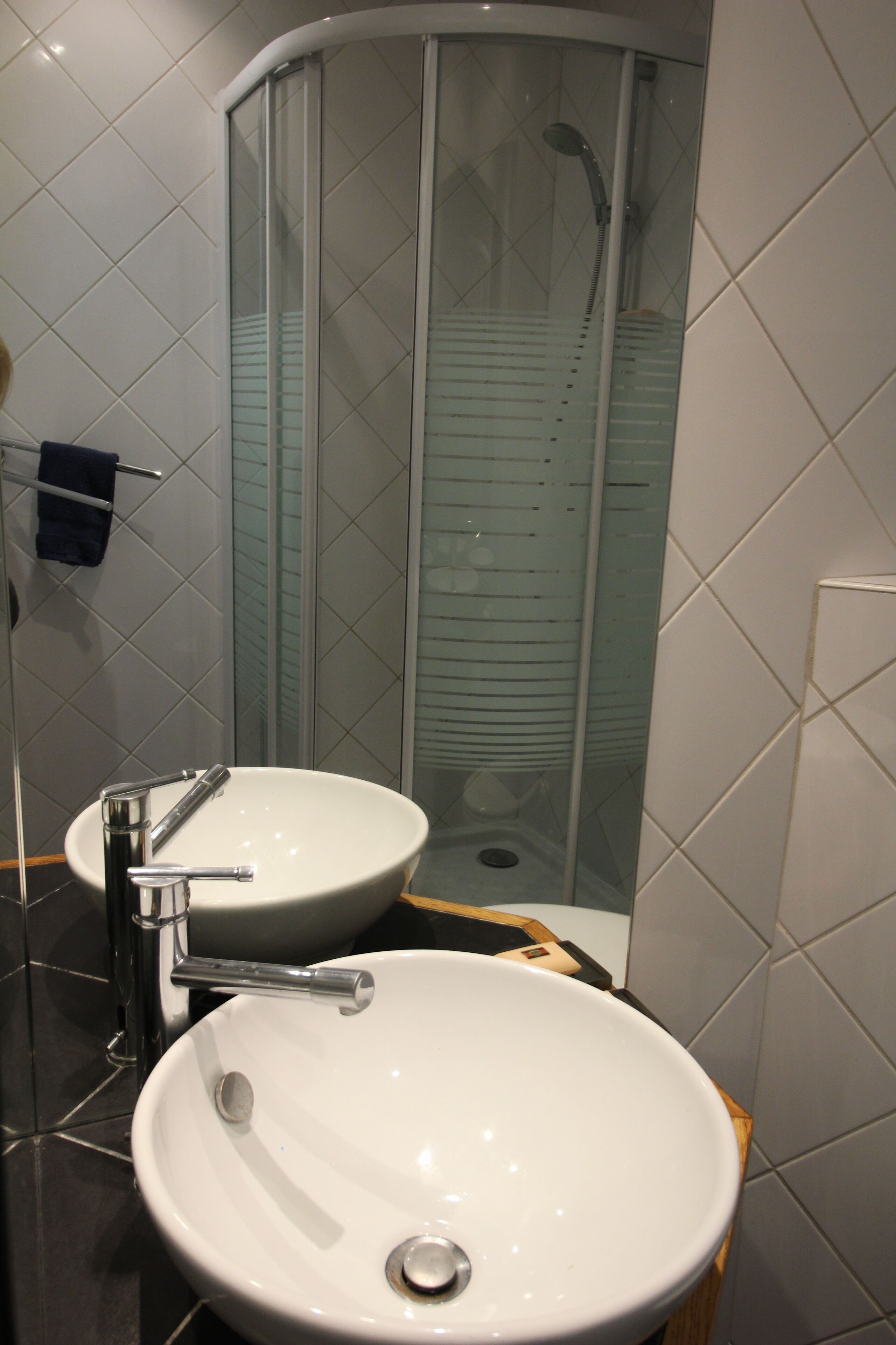 A modern bathroom with a white sink, a glass shower enclosure, and a mirror.