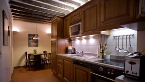 Een keuken met houten kastjes, een magnetron, een fornuis en een spoelbak.