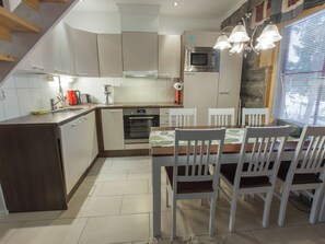 A modern kitchen with a dining area, featuring a microwave, oven, and a dining table with chairs.